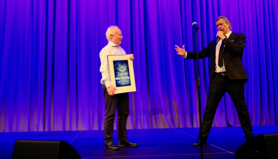 Geir Helge Johnsen med prisen, som er eit bilde laga av Harald Kryvi, saman med Alex Rosén under konferansemiddagen på Aqkva-konferansen.