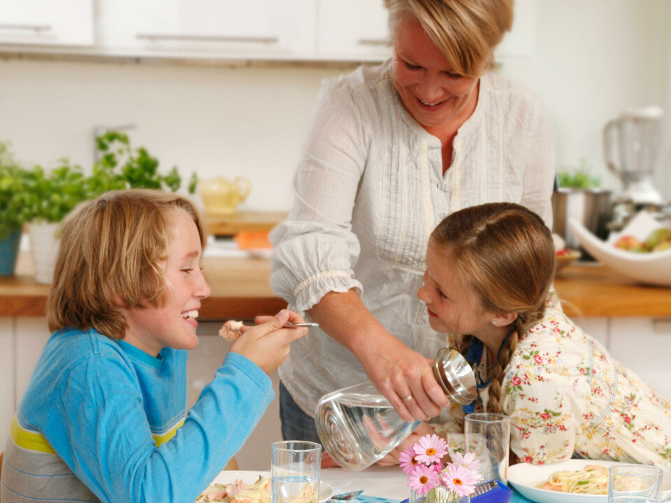 Familie spiser fisk rundt middagsbordet, servering, mor, sønn, datter.