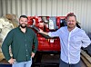 To menn står foran en rød marinemotor i et verksted med industriell bakgrunn.