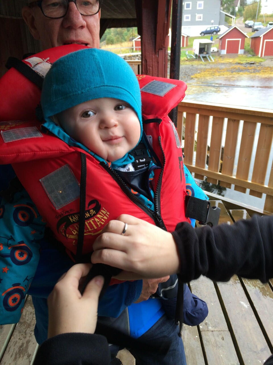 Finn Webb Hoholm (1 år) og bestefar Arnold Hoholm tar på redningsvest før båttur ut til merdkanten for å hilse på fisken under barnas laksefestival. Foto: Marte Sørbø Hoholm.